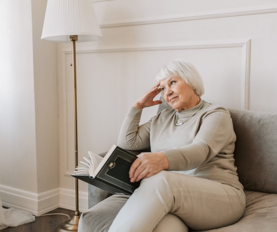 Elderly woman reading a book at RoseShire Festival event.